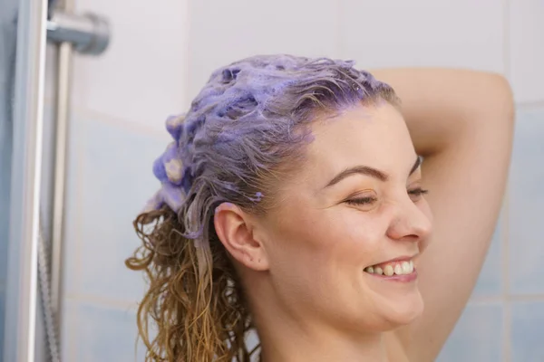 Женщина под душем с цветной пеной на волосах — стоковое фото