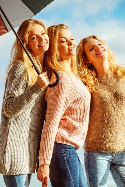 Three women under colorful umbrella