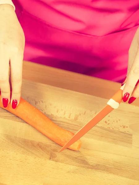 Женщина режет морковь на кухонной доске — стоковое фото