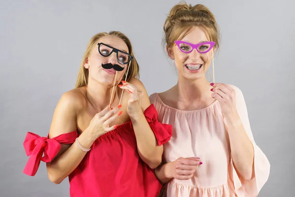 快乐的两个女人拿着纸装饰照片亭面膜眼镜和胡子在棍子上 玩得开心 生日和狂欢节有趣的配件概念 — 图库照片