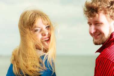 Sevgi dolu genç bir çift kumsalda birlikte vakit geçiriyorlar. Denize yakın oturuyorlar.