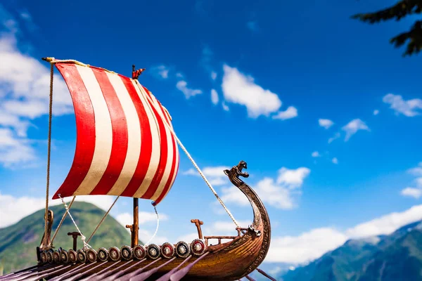 Old wooden viking longboat sails, drakkar boat on fjord shore in Norway. Tourism and traveling concept