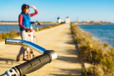 Bisikletli olgun bir kadın San Pedro del Pinatar bölge parkında dinleniyor, Murcia İspanya. Turist eğlencesi. Tatillerde etkinlik