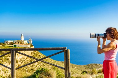 Kameralı kadın turist Mesa Roldán deniz fenerinden fotoğraf çekiyor. Cabo de Gata Nijar Doğal Parkı, Endülüs İspanya.