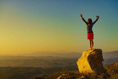 Kameralı turist kadın kolları havada gün batımının tadını çıkarıyor. Almerya, Endülüs 'teki Mesa Roldán bölgesi. Cabo de Gata Doğal Parkı.