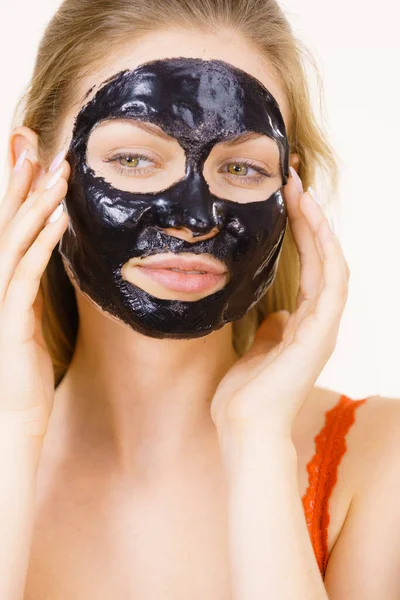Young woman with carbo black peel-off mask on her face, cosmetic ready to remove, on white. Teen girl taking care of oily skin. Beauty treatment. Skincare.