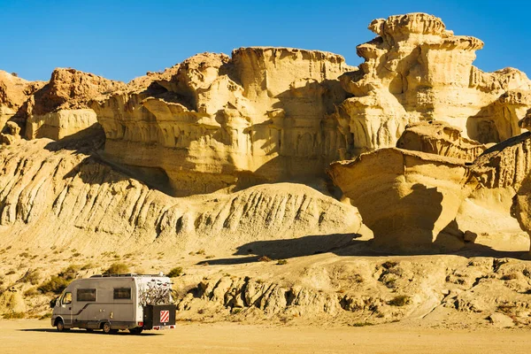 Camper car on parking area at eroded yellow sandstone formations, Enchanted City of Bolnuevo, Murcia Spain. Tourist attraction.