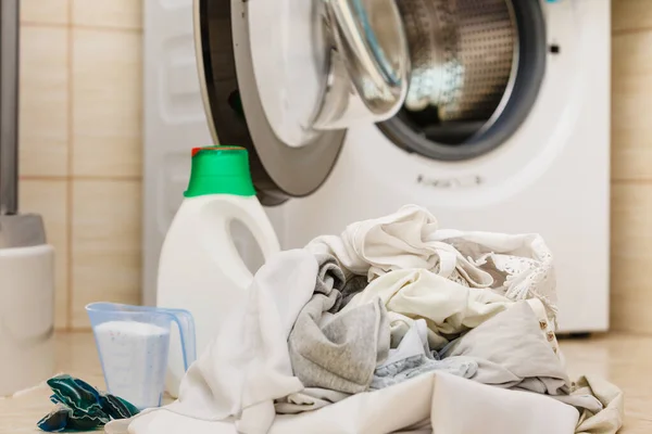 Washing powder detergent and measuring cup next to machine in bathroom. Household duties, clothes laundry obejcts concept.