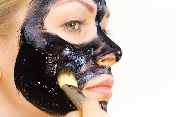 若い女性は顔にブラシ黒デトックス泥マスクを適用します 女の子は肌の世話をする 美の治療だ スキンケア — ストック写真