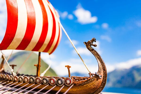 Old wooden viking longboat sails, drakkar boat on fjord shore in Norway. Tourism and traveling concept