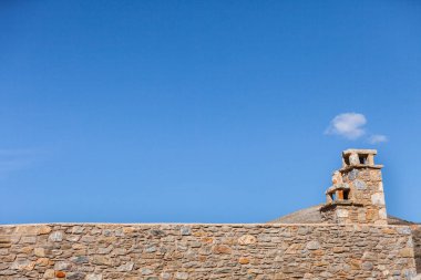 Çatıdaki baca mavi gökyüzüne karşı eski taş tuğlalardan yapılmıştır..