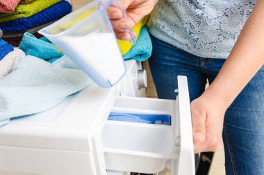 Çamaşır deterjanı ve ölçü kabının makineye dökülmesi. Ev işleri, çamaşır yıkama, obezite konsepti..