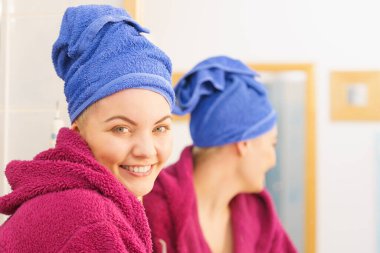 Banyoda duş aldıktan sonra havluyla ve bornozla kendini rahat hisseden genç bir kadın.