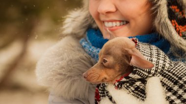 Genç bir kadın soğuk kış gününde en iyi arkadaşını sıcak battaniye eşarbına sardı. Hayvan koruma programı. Evlat edinme kavramı