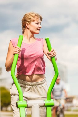 Spor salonunda spor kıyafetli aktif bir kadın, eliptik antrenör makinesinde egzersiz yapıyor. Spor uygunluğu.