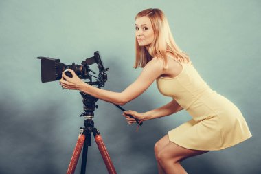 Fotoğrafçı kız fotoğraf çekiyor. Çekici, modaya uygun, sarışın bir kadın mavi kamerayla fotoğraf çekiyor.