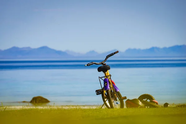 Child bike with safety helmet parked on beach seashore in summer. Lofoten archipelago Norway. Holidays and adventure.