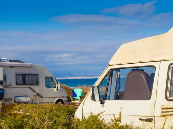 Campers, recreational vehicles on mediterranean coast in Spain. Camping on nature beach. Holidays and travel in motor home.