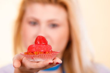 Şekerler, abur cuburlar, diyet kavramının cazibesi. Bir kadın lezzetli bir kek tutuyor.