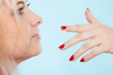 Diyet, tatlı cazibesi, lezzetli yemek konsepti. Parmaktan krem şanti yalayan ya da dudak nemlendirici süren, kırmızı tırnaklarını gösteren bir kadın.