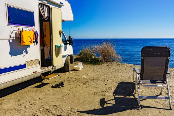 Wild camping on sea shore. Camper car rv with clothes hanging to dry. Holidays with motor home.