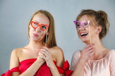 Sopanın üzerinde iki mutlu kadın gözlük takıyormuş gibi yaparak eğleniyorlar. Fotoğraf ve karnaval komik aksesuar konsepti.