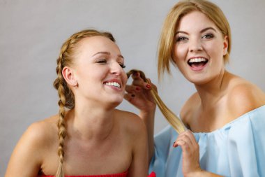 Kadın en iyi arkadaşının saç stiline hayran, uzun saçları örgülü.