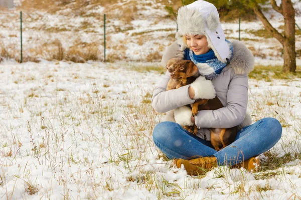 雪の中で外で遊んでいる若い女性 女性遊びますとともに彼女の小さな純血犬子犬で寒い冬の日 — ストック写真