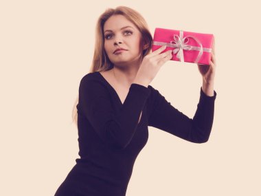 Neşeli kız hediyesini tutuyor pembe hediye kutusunu sallıyor, içinde ne olduğunu tahmin etmeye çalışıyor. Noel mevsimi kutlama konsepti.