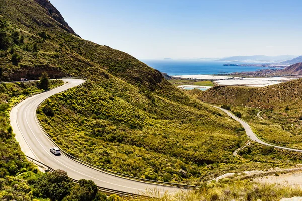 İspanyol dağları manzarası ve vadide birçok serası olan deniz kıyısı manzarası. Castillitos Bataryası 'na giden dolambaçlı yol.