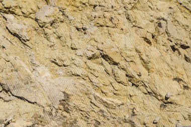 Grunge duvar taşı ya da sert doğa kayası. Dağdan ya da kayalıklardan kayarak kayan kayalardan korunmak için ağlı..