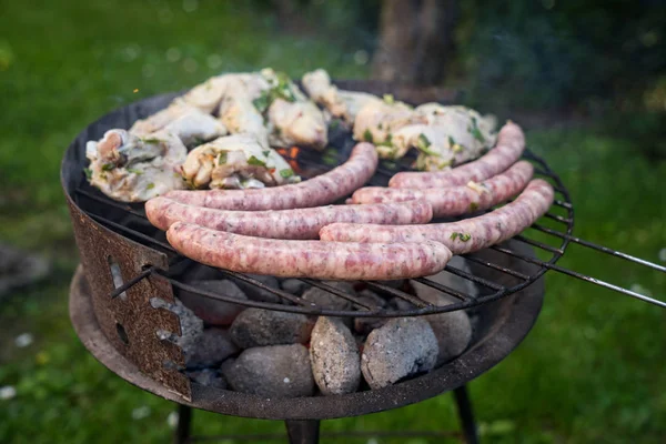 Grill garden party with sausages and meat on hot briquette