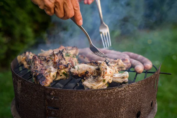 Grill garden party with sausages and meat on hot briquette