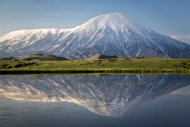 Early in the morning in Klyuchevskoy Park near the lake, the Plosky and Ostry Tolbachik volcanoes in a mirror image clipart