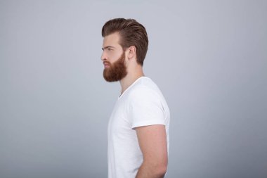 Son moda saç modeli ile yakışıklı erkek profil vurdu ve beyaz arka plan üzerinde izole kalın kırmızı sakal, sakal, bir kenara ciddi ifade ile görünüyor vardır