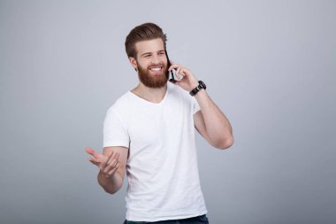 Beyaz arka plan üzerinde cep telefonuyla konuşan mutlu yakışıklı sakallı adam
