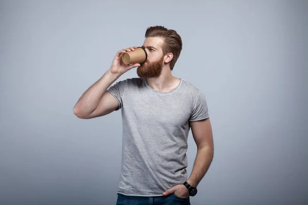 Joven Hombre Barbudo Guapo Camiseta Gris Bebiendo Taza Café Sosteniendo —  Fotos de Stock