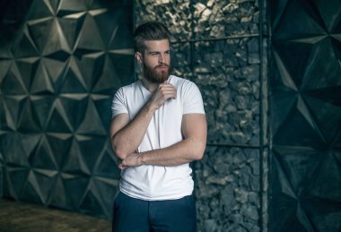 Mükemmel bir adam. Çeneme elini tutarak ve kamera modern gri arka plan karşı dururken bakarak genç yenilikçi.