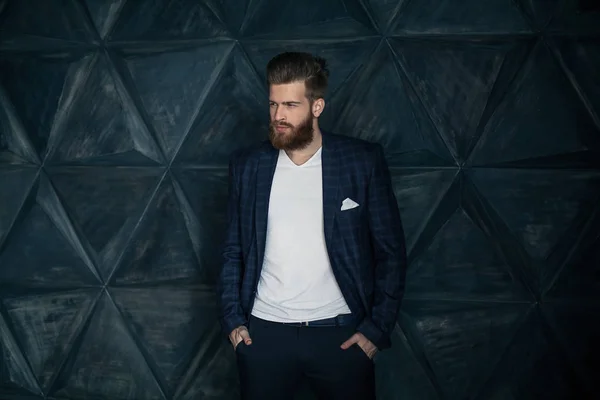 Ready to go. Handsome man with long hair and beard looking looking sideways while standing against grey background.