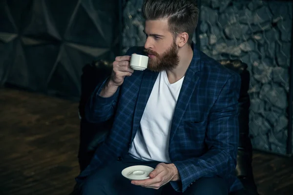 Forretningsmann med en kopp kaffe i nærheten av moderne bakgrunn – stockfoto