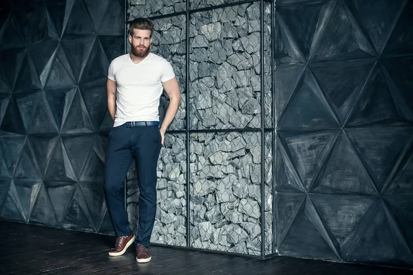 Trendy look. Full length of handsome young man looking away and keeping hands in pockets while standing against grey background — Stock Photo, Image