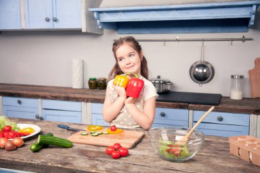 Sevimli küçük bir kız bir Bulgar biber tutarak yatay bir fotoğrafı