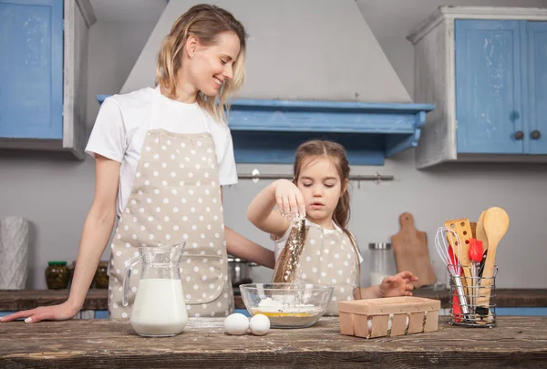 Konzentrieren Sie sich auf die Hand der Tochter, die Mehl in die Schüssel gibt. Mutter und tochter im die küche kochen mafins — Stockfoto