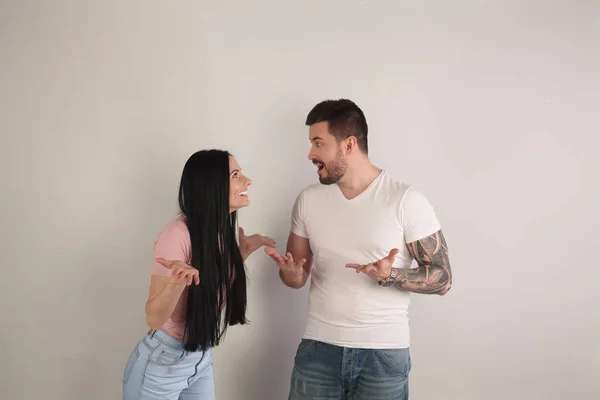 Hermoso chico y chica están mirando sorprendidos el uno al otro, no entienden lo que está pasando a su alrededor. se paran frente al fondo blanco — Foto de Stock