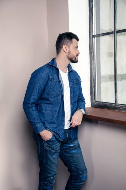 Genç yakışıklı düşünceli adam evde düşünme ve pencereye bakarak pencerede duruyor