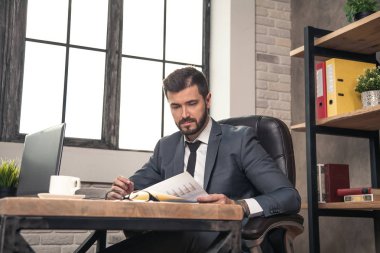 ofiste masasında genç şık yakışıklı işadamı okuma belgeleri