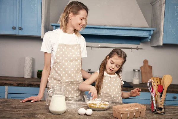 Mutter und Tochter bereiten in der Küche Teig vor, backen Plätzchen. Mama bringt ihrer Tochter bei, den Teig aus Mehl, Milch und Eiern zu kneten. Wenig Helfer. hausgemachtes Essen — Stockfoto
