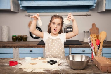 Mutfakta küçük kız mutfakta farklı şekillerde hamur kurabiye yapıyor. Küçük yardımcı, ev yapımı gıda