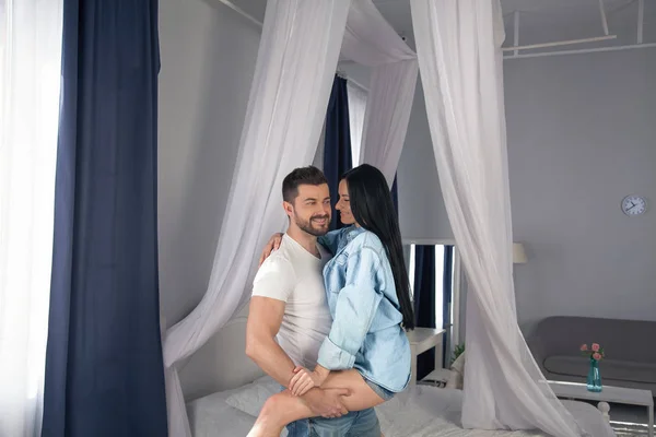 El amor está en el aire. Hermosa pareja joven que se une y sonríe mientras se sienta en el dormitorio — Foto de Stock