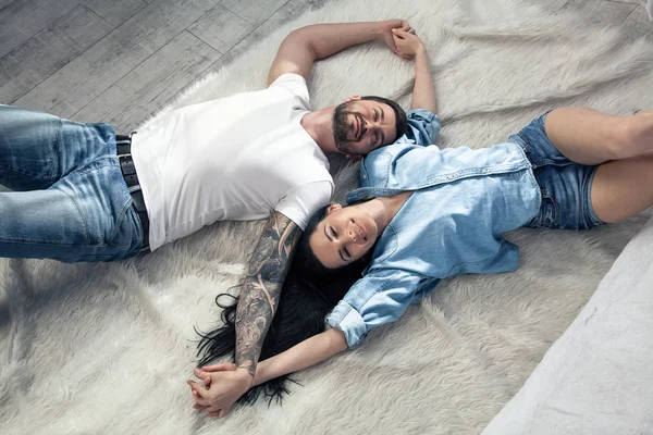 Vista superior de una hermosa pareja tendida sobre fondo blanco. chica con el pelo largo y oscuro. ellos están enamorados — Foto de Stock